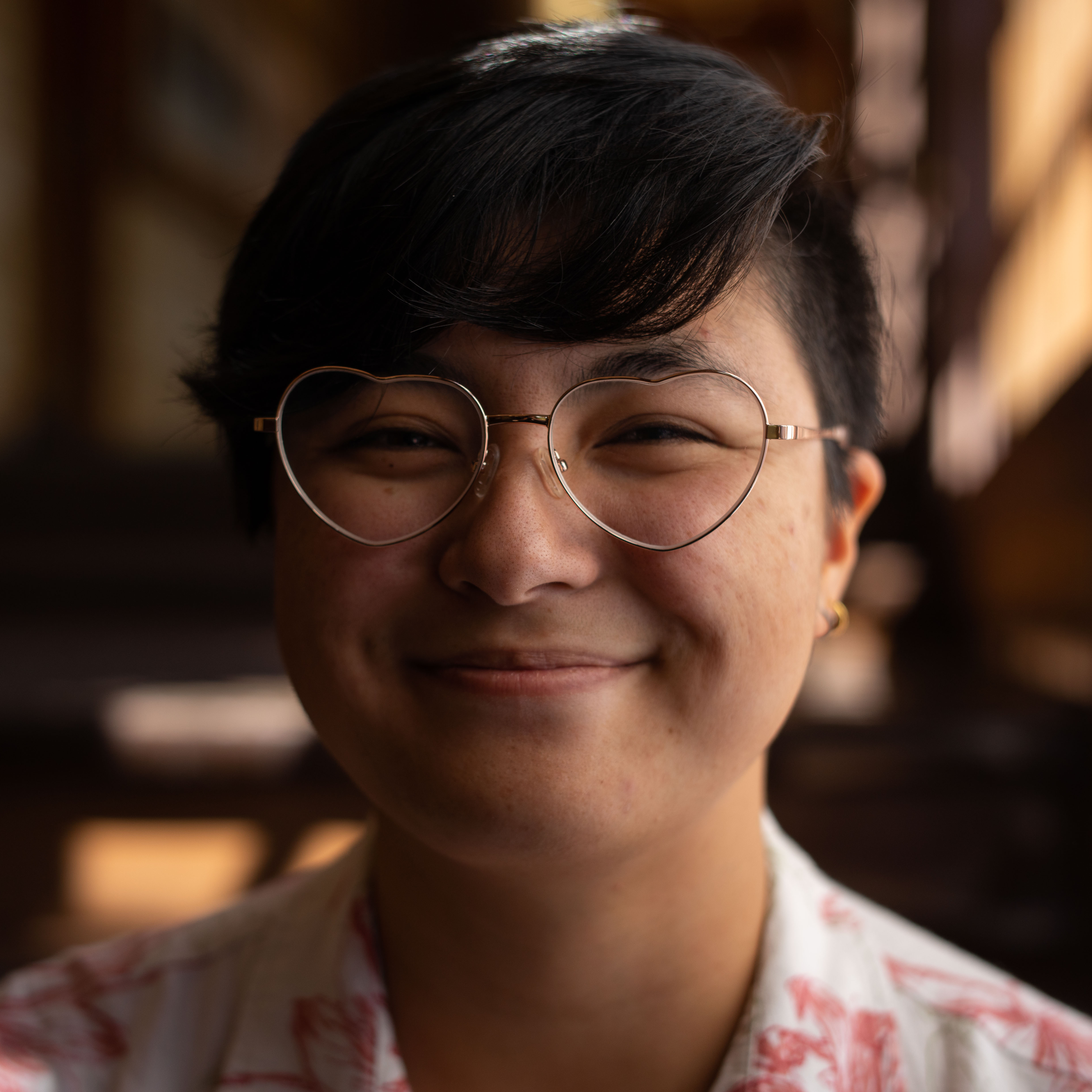 Headhot photo of me, an Asian person with short black hair, brown eyes and heart-shaped glasses