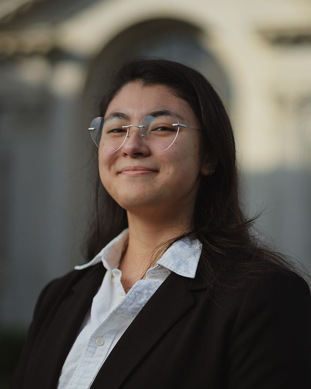 profile of me smiling with black hair ponytail wearing white shirt and black suit and heart shaped glasses